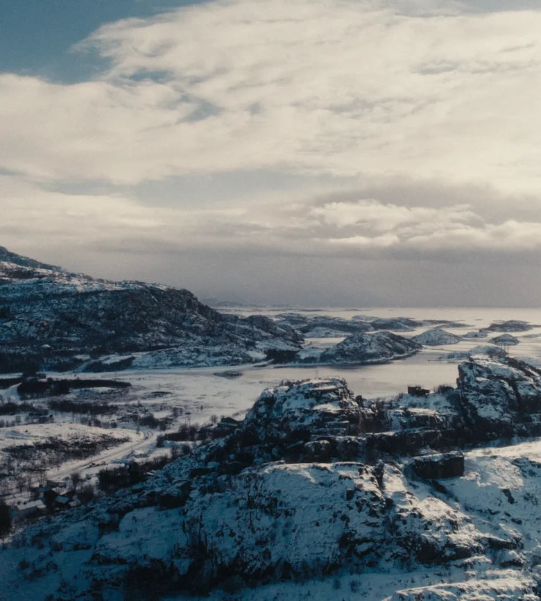 A woman on a snowy Norwegian fjord holding a Frøya jar
